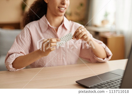 Close up of unrecognizable young woman as doctor showing blister of pills camera via video chat and consulting client online copy space 113711018