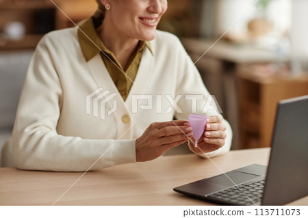 Top view closeup of female health specialist holding menstrual cup while consulting client online via laptop copy space 113711073