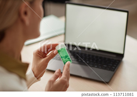 Close up of unrecognizable female doctor holding bottle of pills and talking to client online via laptop copy space Close up of unrecognizable female doctor holding bottle of pills and talking to client online via laptop copy space 113711081