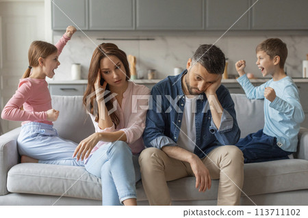 Two preteen children screaming at each other, stressed parents sitting beside them Two preteen children screaming at each other, stressed parents sitting beside them 113711102