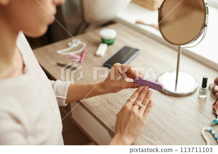 Closeup of unrecognizable young woman doing manicure at home and using nail file copy space Closeup of unrecognizable young woman doing manicure at home and using nail file copy space 113711103
