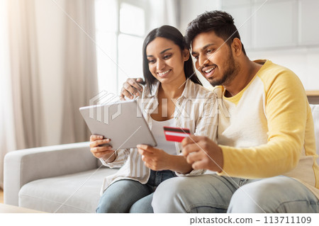 Eastern millennial couple browsing on tablet at home Eastern millennial couple browsing on tablet at home 113711109