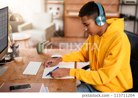 Individual writing in notebook at desk Individual writing in notebook at desk 113711204
