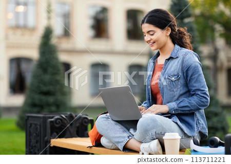 Focused woman student working on laptop outside Focused woman student working on laptop outside 113711221