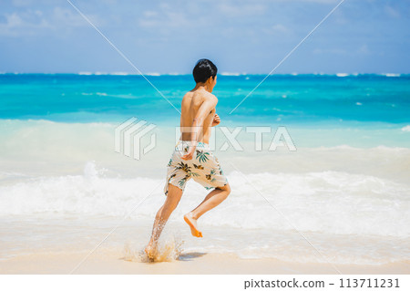 穿著泳衣的年輕人跑向夏威夷沙灘上的碧綠海洋 113711231