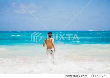 穿著泳衣的年輕人跑向夏威夷沙灘上的碧綠海洋 113711238