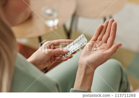 Close up of unrecognizable woman taking birth control pill at home in open hand copy space Close up of unrecognizable woman taking birth control pill at home in open hand copy space 113711268
