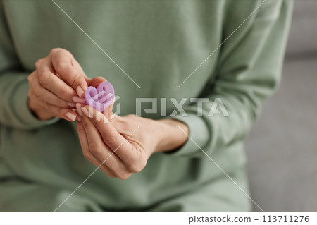 Close up of unrecognizable woman holding menstrual cup to camera and demonstrating folding technique copy space 113711276