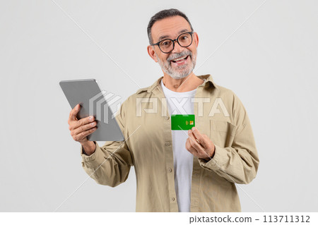 Elderly man holding a tablet and credit card 113711312