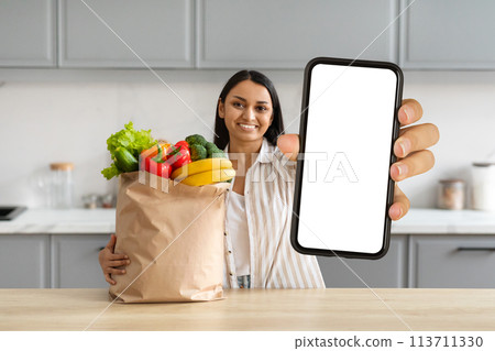 Happy young indian woman order grocery online, showing smartphone Happy young indian woman order grocery online, showing smartphone 113711330