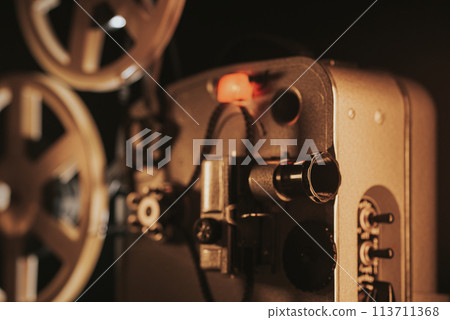 Retro projector playing motion picture. dark room. Timeless flicker of old films Retro projector playing motion picture. dark room. Timeless flicker of old films 113711368