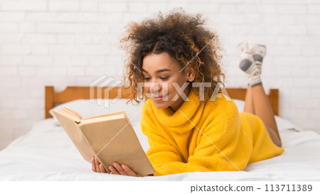 Relaxed girl reading book in bed at home 113711389