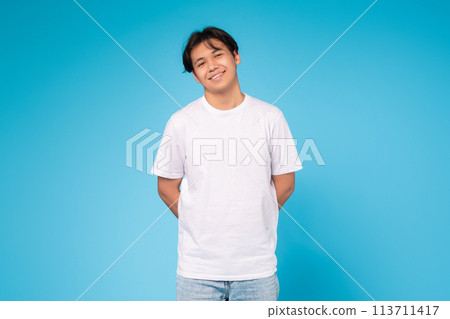 Smiling young guy standing casually, blue background Smiling young guy standing casually, blue background 113711417