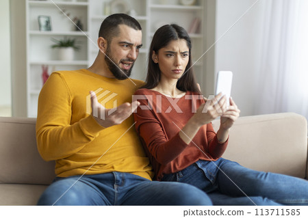 Couple looking at phone with expressions Couple looking at phone with expressions 113711585