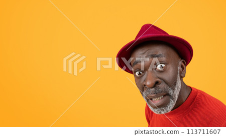 Surprised senior black man in red hat and sweater with a comically raised eyebrow Surprised senior black man in red hat and sweater with a comically raised eyebrow 113711607
