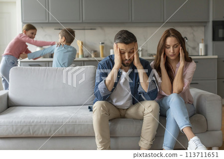 Stressed parents with kids playing in background 113711651