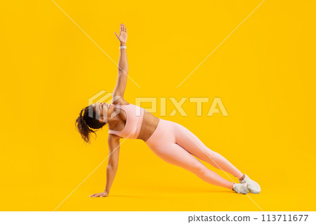 Side plank pose by fitness woman in pink attire 113711677