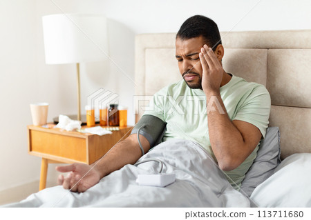 Man checking blood pressure in bed 113711680