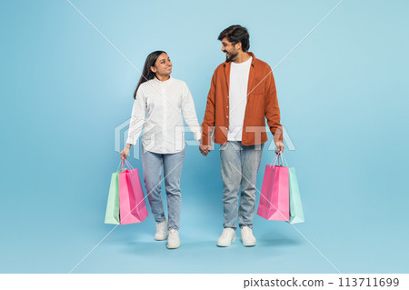 Couple walking with shopping bags looking at each other 113711699