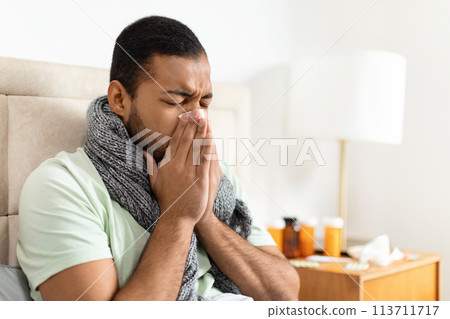 Man with scarf looking ill, sneezing Man with scarf looking ill, sneezing 113711717