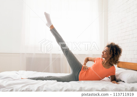 Girl exercising in bed in the morning Girl exercising in bed in the morning 113711919