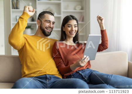 Couple rejoicing while looking at tablet Couple rejoicing while looking at tablet 113711923