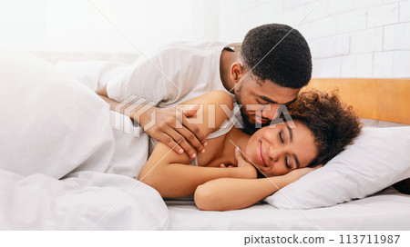 Handsome man kissing woman on cheek under in bed Handsome man kissing woman on cheek under in bed 113711987