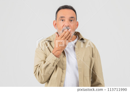 Mature man looking surprised and covering mouth 113711990