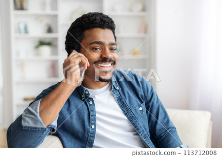 Smiling Black Man Enjoying a Conversation on the Phone Indoors 113712008