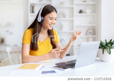 Casual woman with headphones at laptop at home office 113712028