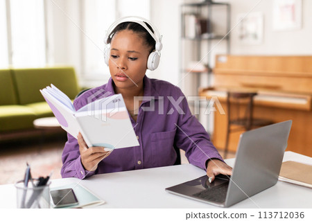Lady student multitasking with book and laptop 113712036