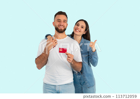 Happy couple showing a credit card on blue background Happy couple showing a credit card on blue background 113712059