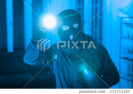 Burglar with flashlight in a dark room 113712107