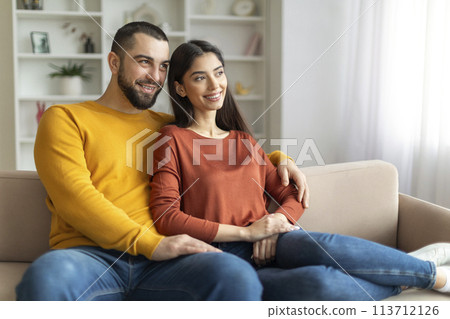 Couple sitting closely on their couch 113712126