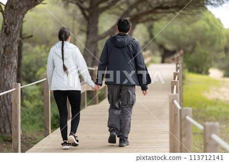 A man and woman are walking on a wooden bridge 113712141