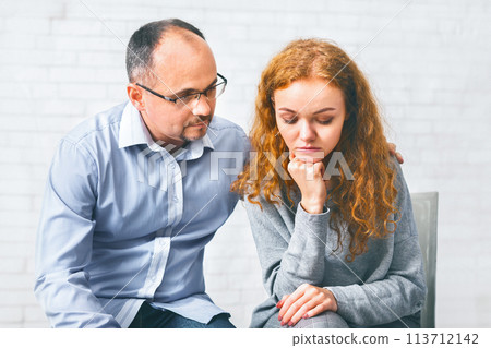 Caring husband supporting his depressed wife at marriage therapy session Caring husband supporting his depressed wife at marriage therapy session 113712142