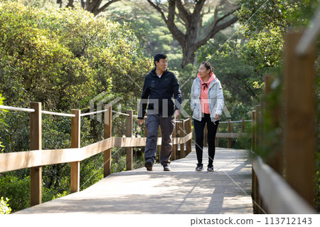 A man and woman are walking on a wooden bridge A man and woman are walking on a wooden bridge 113712143