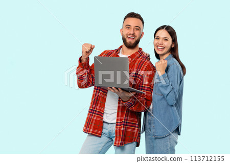 Happy couple with laptop celebrating on blue background 113712155