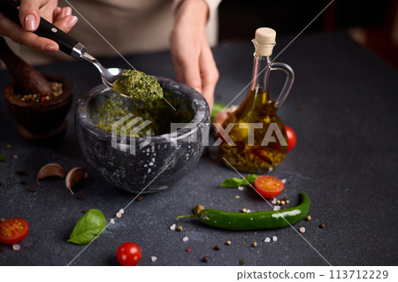 woman mixing green sauce in a stone marble mortar 113712229
