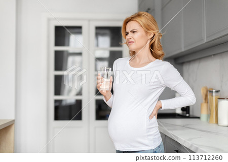 Pregnant woman feeling unwell with glass of water 113712260