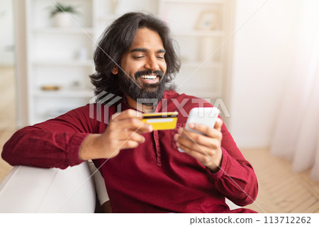 Happy man shopping online with card at home 113712262