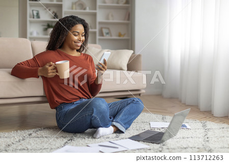 Young Black Woman Enjoying Coffee and Using Smartphone Indoors 113712263