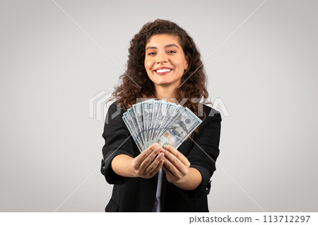 Woman holding a fan of US dollar bills 113712297