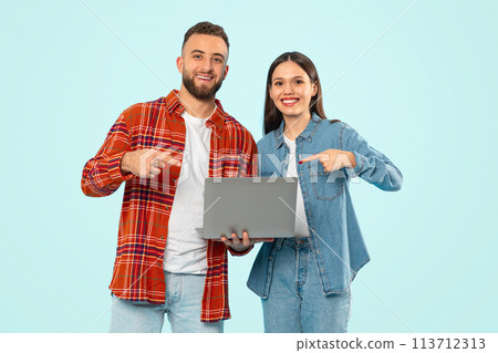 couple holding laptop and pointing fingers at computer together, studio 113712313