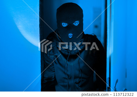 Mysterious figure of man in blue-lit apartment corridor Mysterious figure of man in blue-lit apartment corridor 113712322