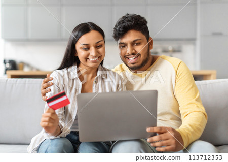 Indian Man and Woman Sitting on Couch Looking at Laptop Indian Man and Woman Sitting on Couch Looking at Laptop 113712353