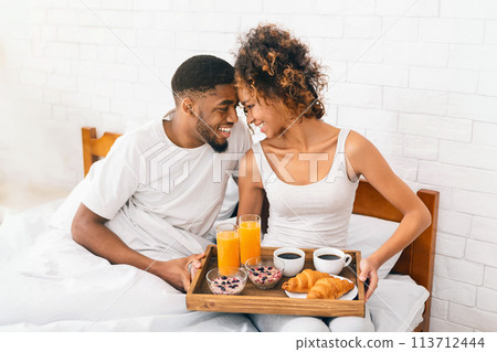 Happy black couple enjoying breakfast in bed Happy black couple enjoying breakfast in bed 113712444