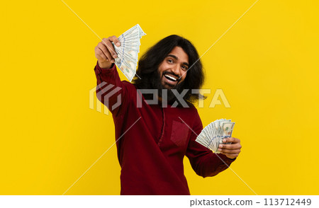 Cool eastern guy showing money cash, yellow studio background 113712449