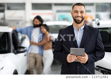 Smiling salesman with clients in the background 113712461