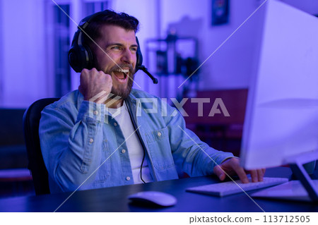 Gamer enthusiastically talking into mic at home Gamer enthusiastically talking into mic at home 113712505